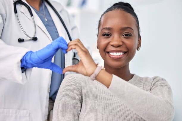 Woman smiling make a heart hand sign with doctor.